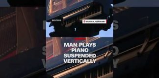 Man plays piano suspended vertically